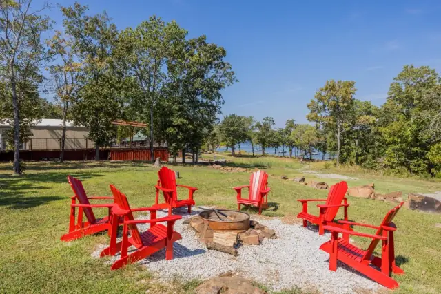 Fire pit with red Adirondack chairs and lake view